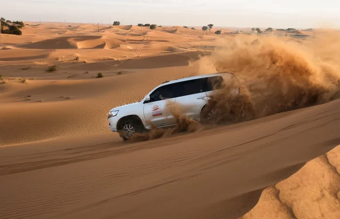 White Toyota Land Cruiser dune bashing across the Dubai desert
