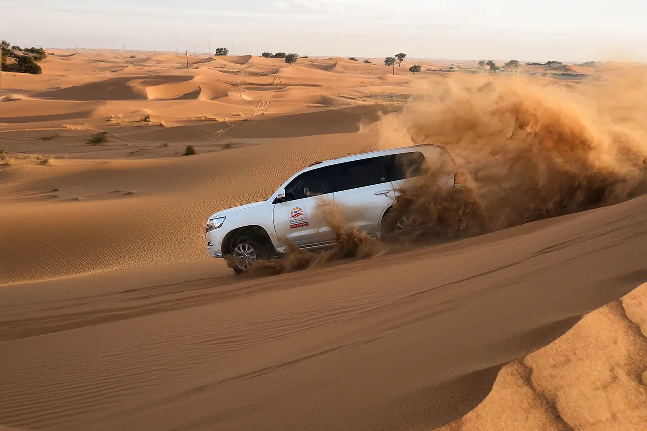 White Toyota Land Cruiser dune bashing across the Dubai desert